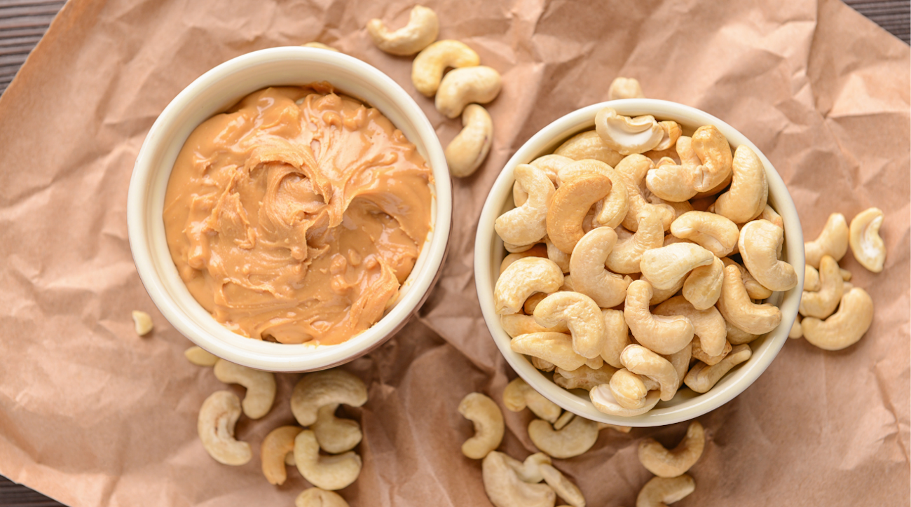Zwei weiße Schalen mit Cashewmus und Cashewkernen